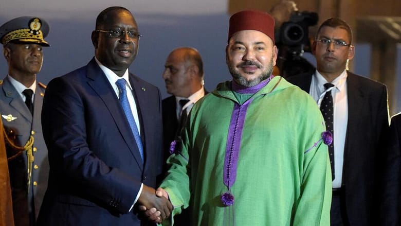 Moroccan King Mohammed VI (foreground R) is welcomed by Senegalese president  Macky Sall(L) upon his arrival at Dakar's airport at the start of his state visit, on November 6, 2016. / AFP PHOTO / SEYLLOU